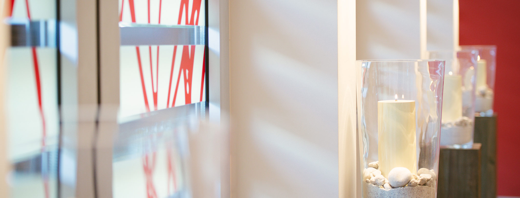 Nahaufnahme einer brennenden Kerze in einem Glasgefäß, umgeben von Dekorationselementen in einem Grieneisen Bestattungsinstitut.